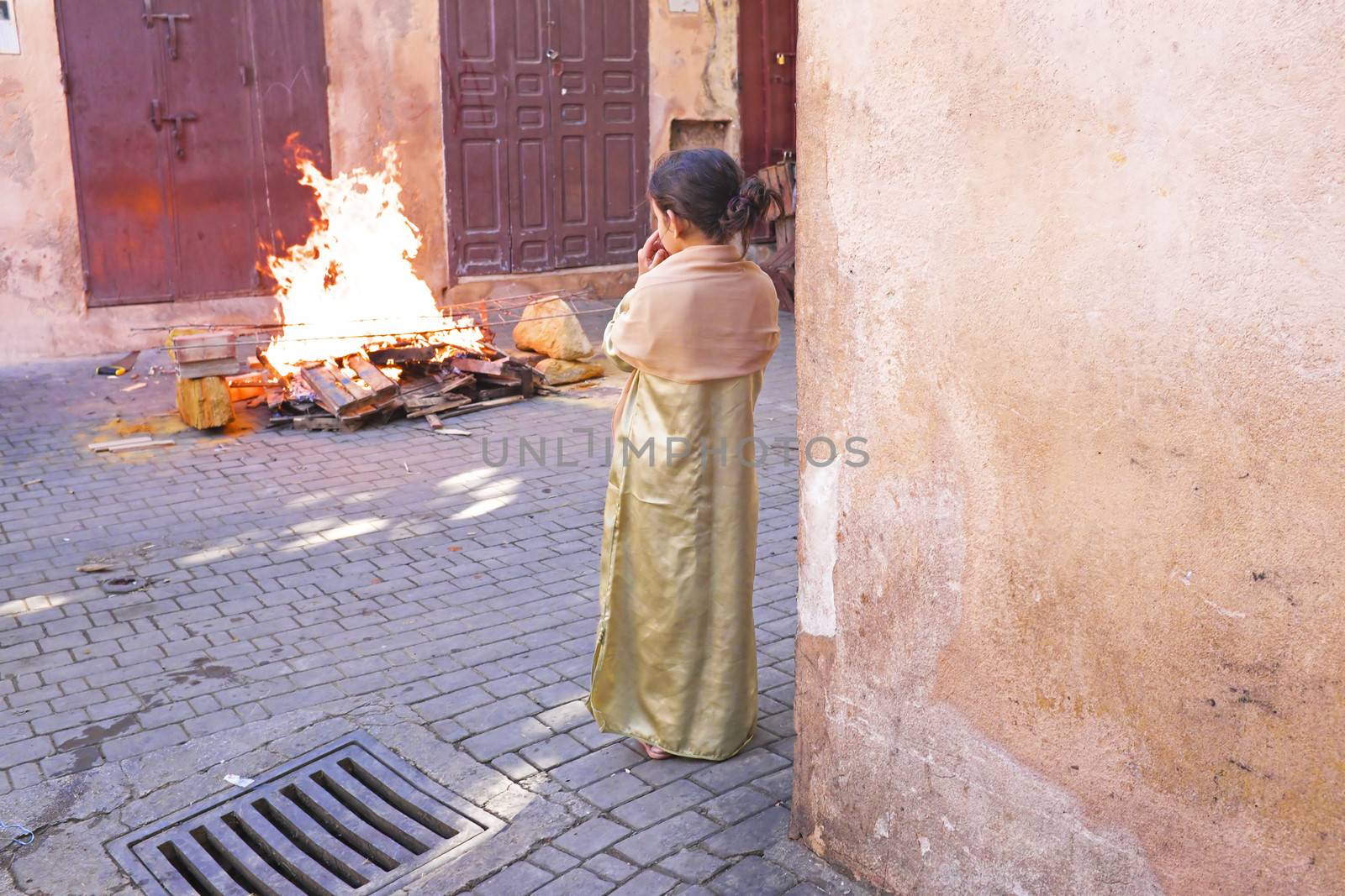 FES, MAROCCO - October 15 : Girl watching the fire on Eid al-Adha, October 15, 2013. The festival is celebrated by sacrificing a lamb or other animal and distributing the meat to relatives, friends, and the poor.