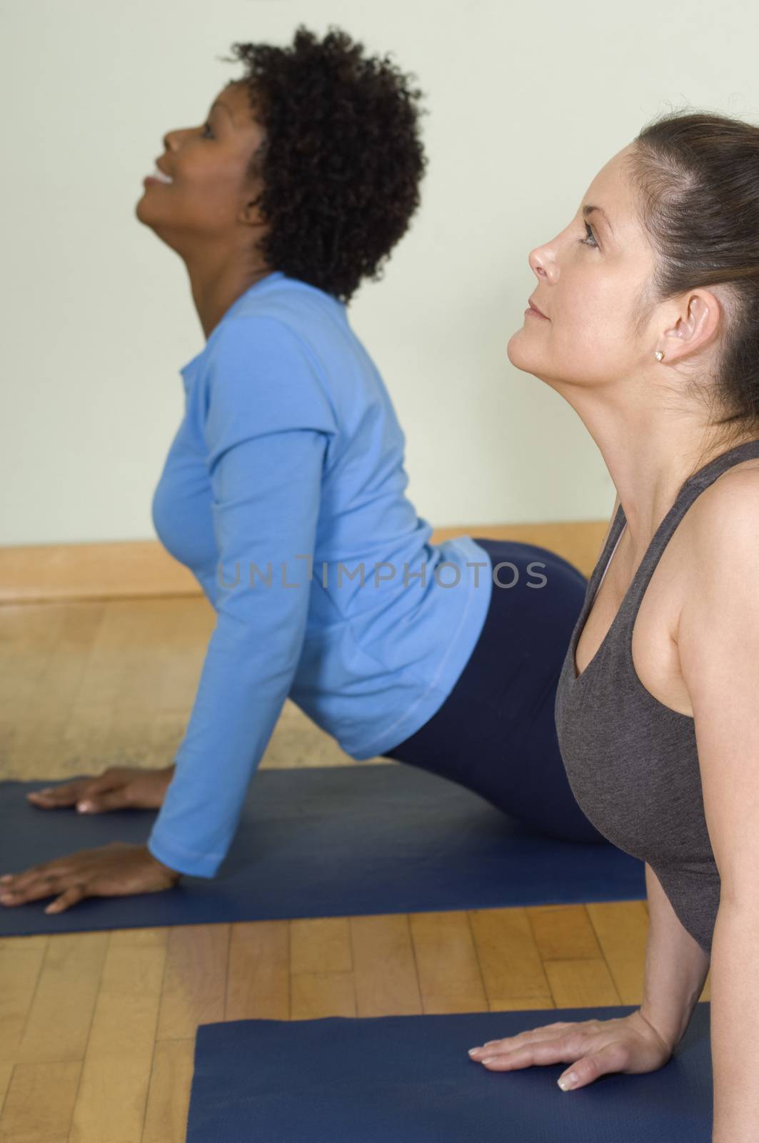 Women performing yoga on mat by moodboard