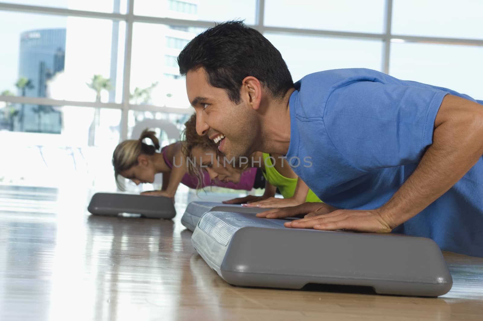 Happy man and women doing pushups in exercise class by moodboard