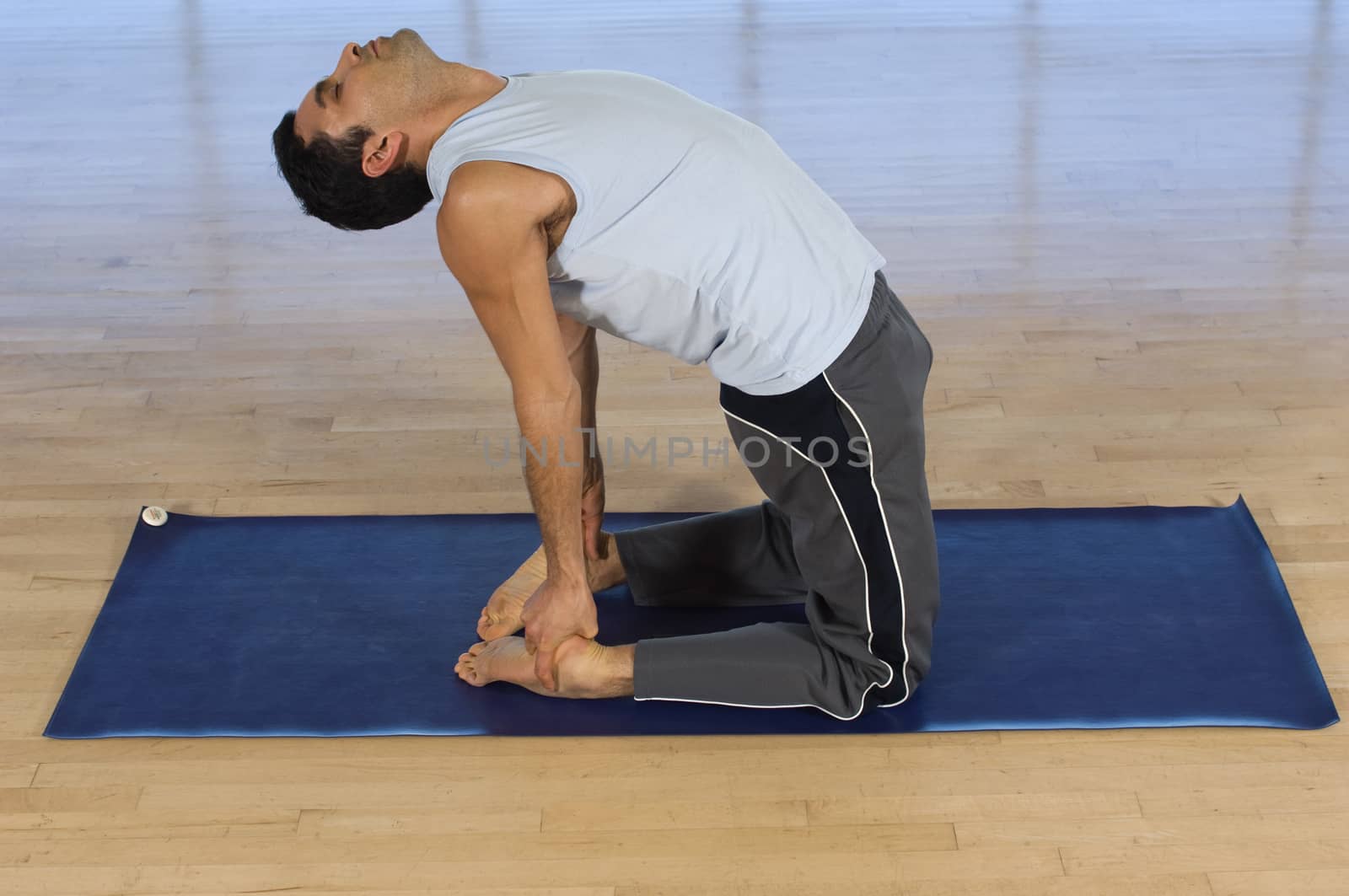 Side view of a middle aged man doing yoga on mat by moodboard