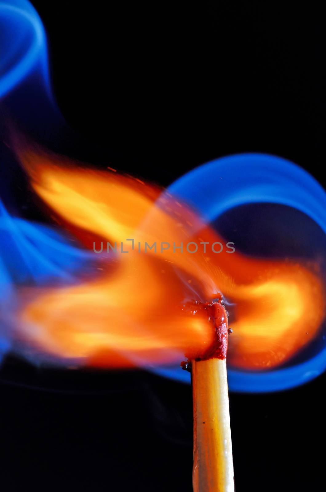 Burning match with blue smoke on black background