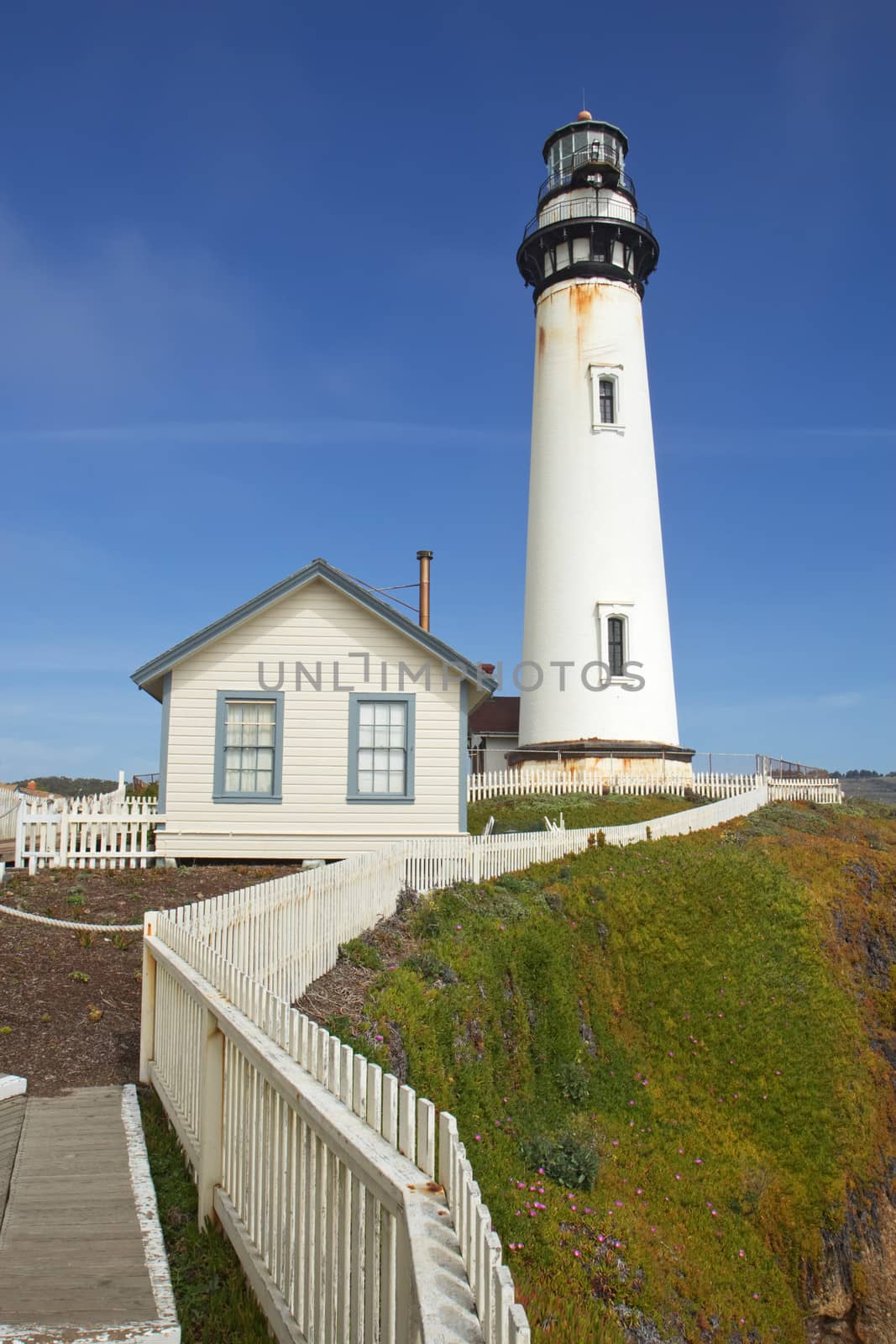 The Pigeon Point Lighthouse and white picket fence located in Pigeon Point Light Station State Historic Park between Half Moon Bay and Santa Cruz on the central California coast