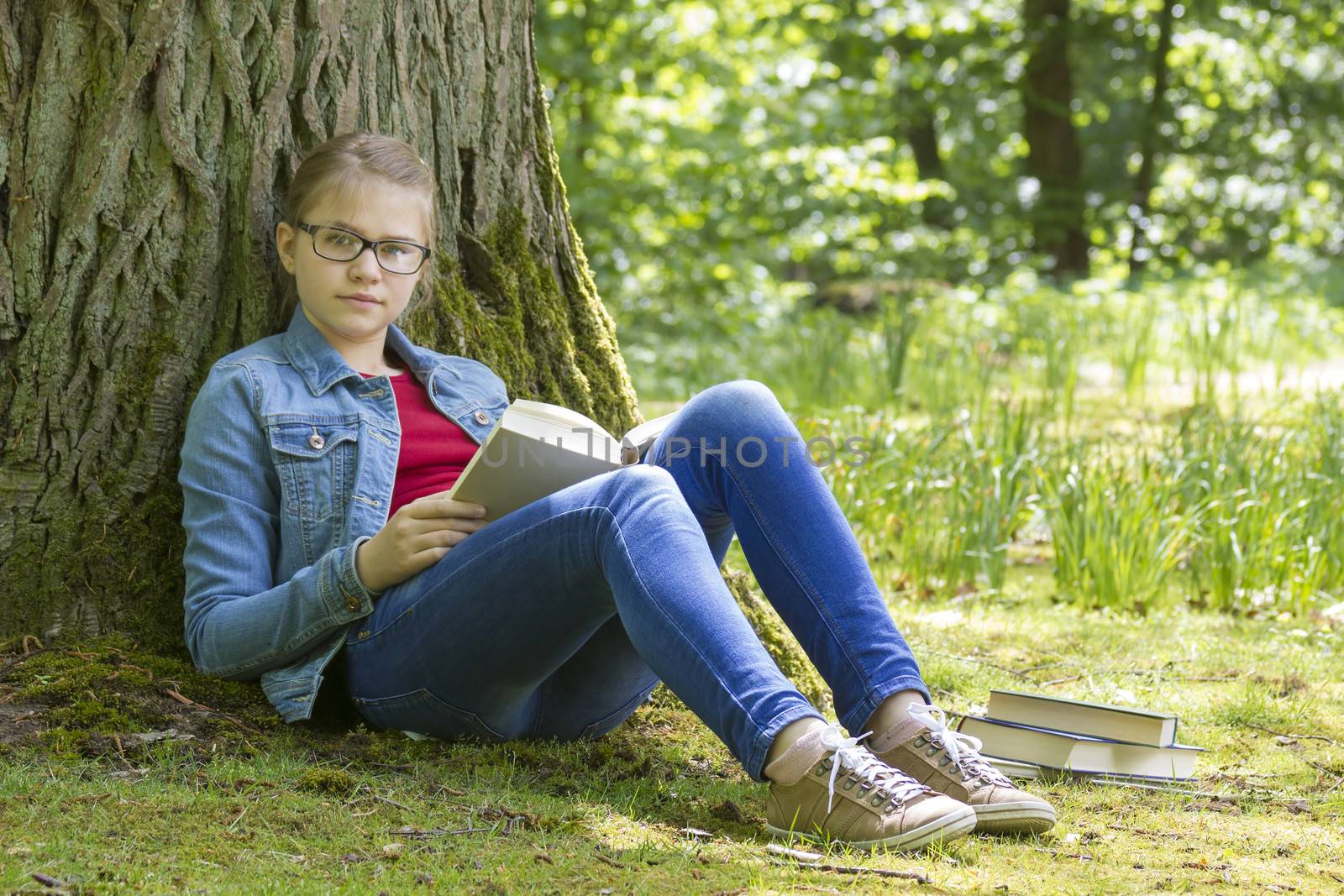Young girl reading book in park in spring day 