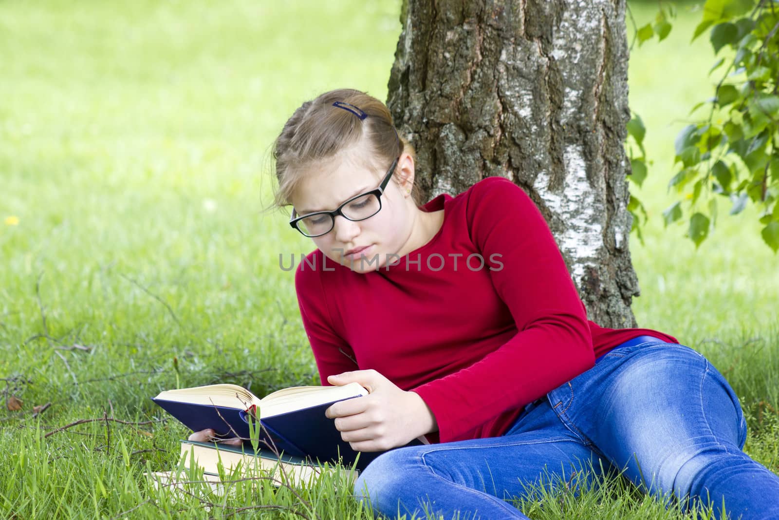 Young girl reading book in park in spring day by miradrozdowski