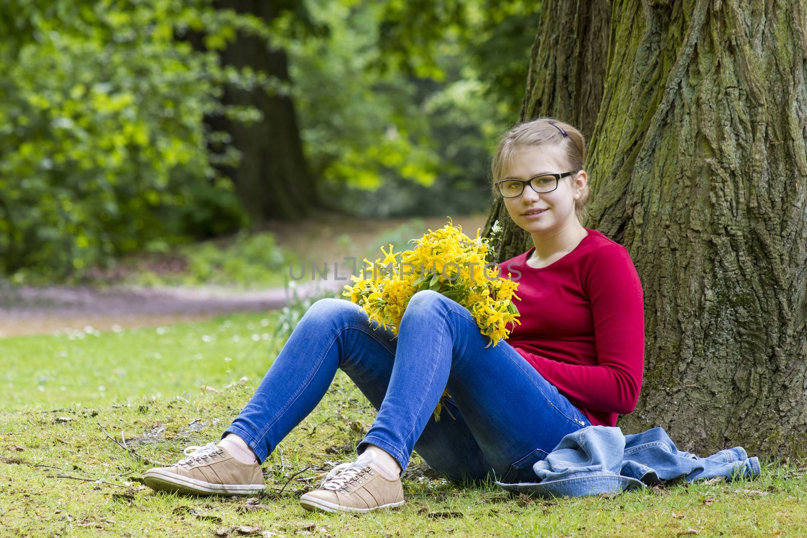 Smiling girl with big bouquet of spring flowers sitting in the park