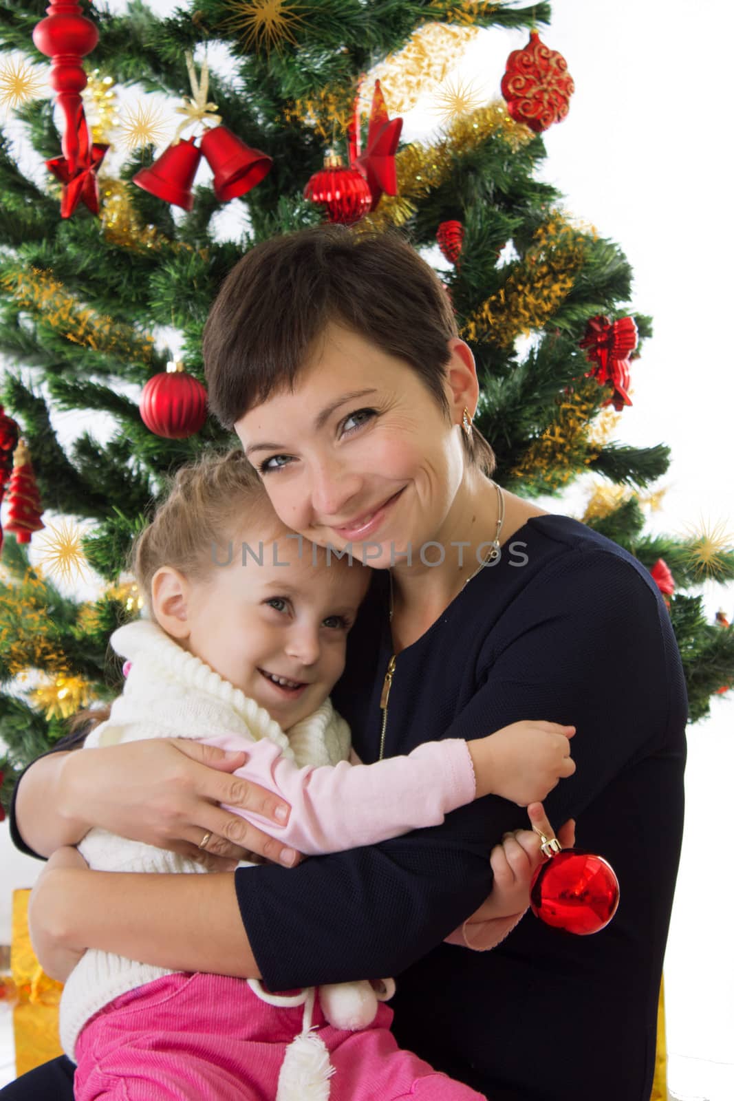 Happy mother hugging daughter under Christmas tree