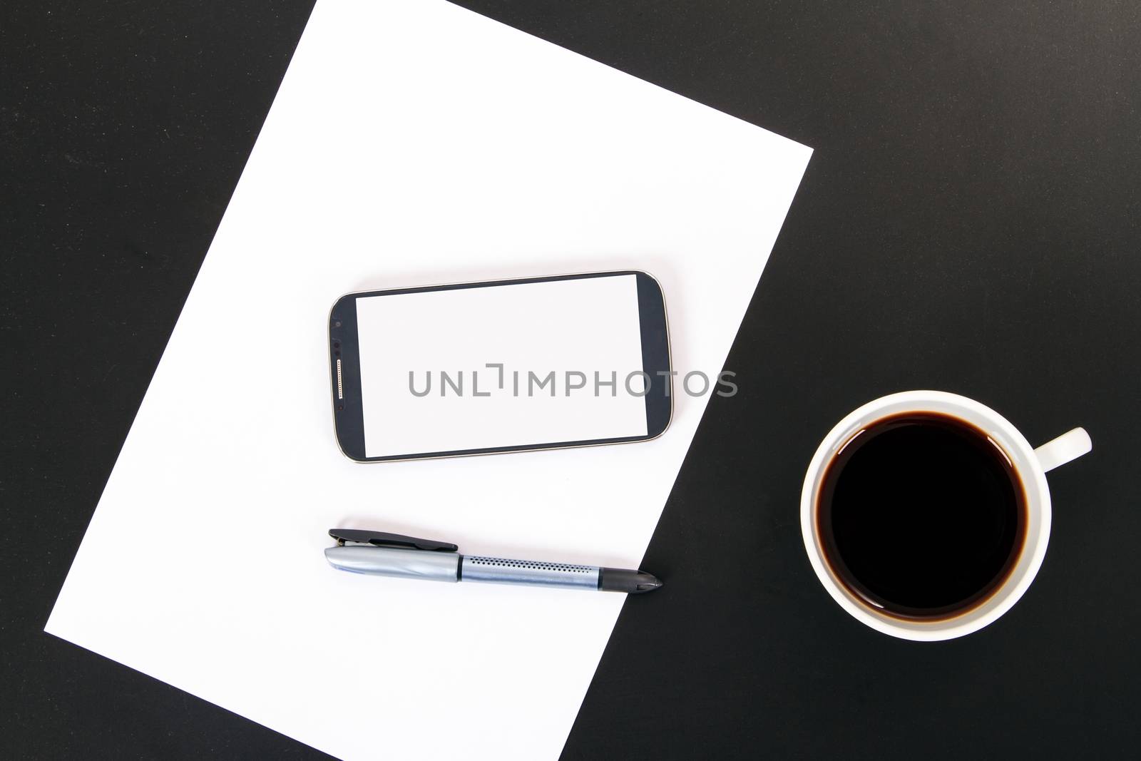 Smart phone with blank, white screen, ceramic coffee cup, pen and empty paper, top view on wooden table.