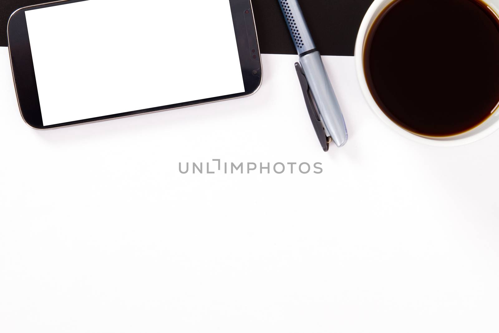 Smart phone with white, blank screen, empty paper, pen and black coffee in white cup on wooden table.