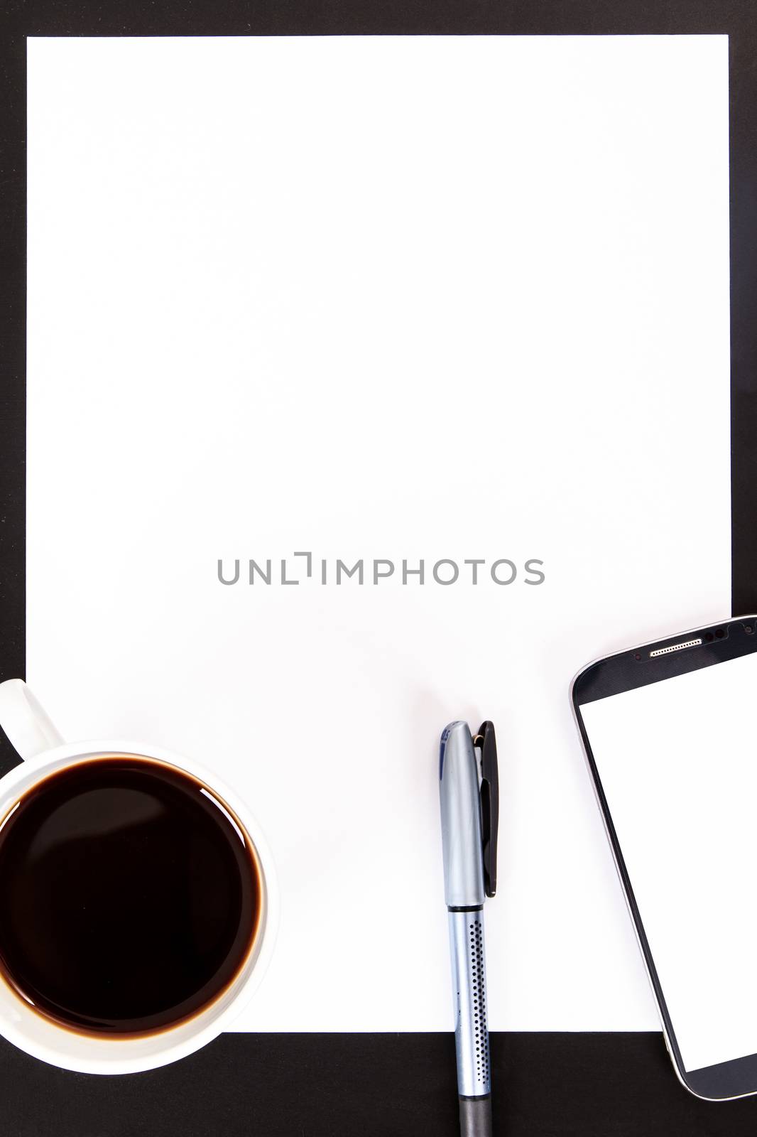 Smart phone with white, blank screen, empty paper, pen and black coffee in white cup on wooden table.