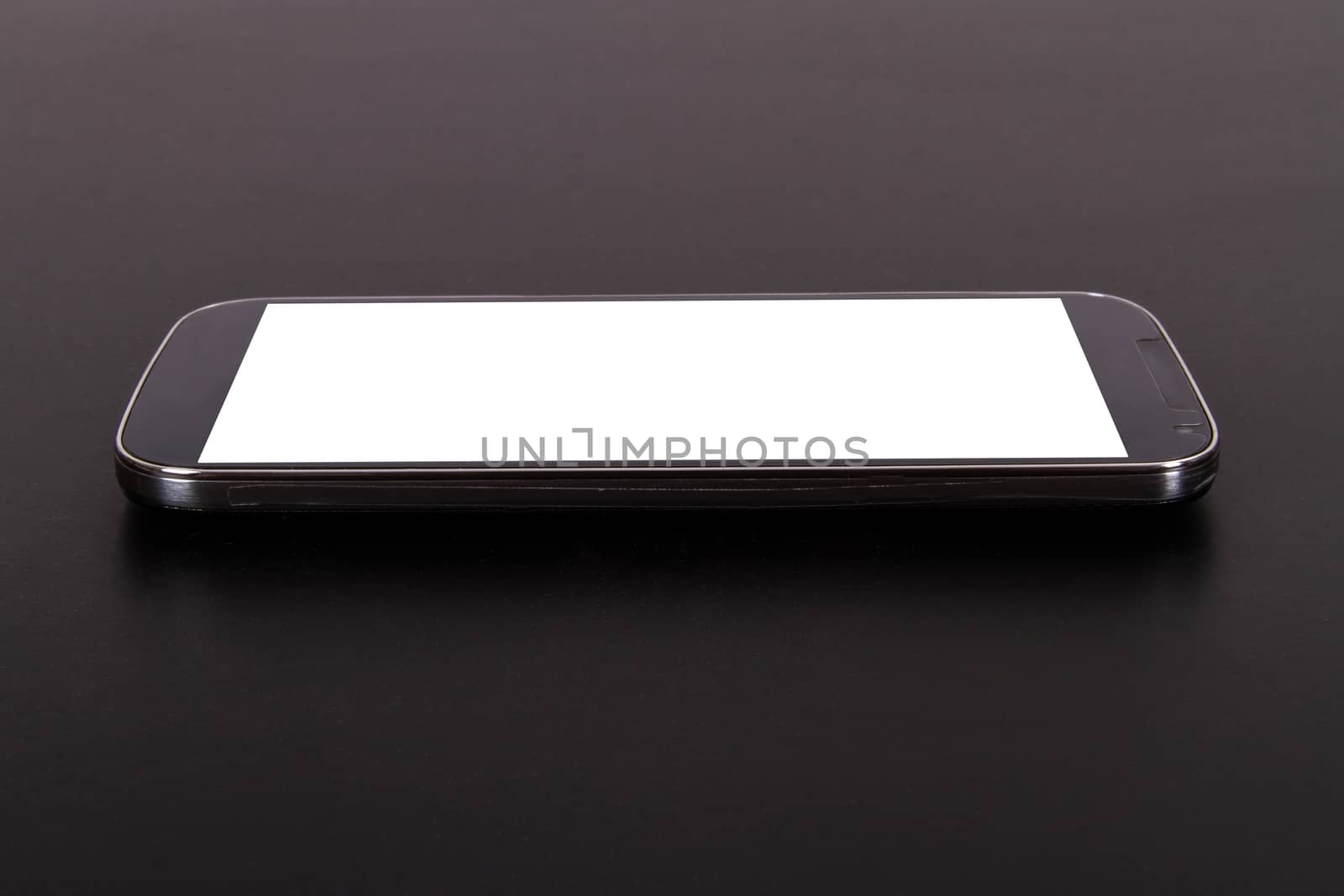 Smart phone with blank, white screen, side view on wooden table.