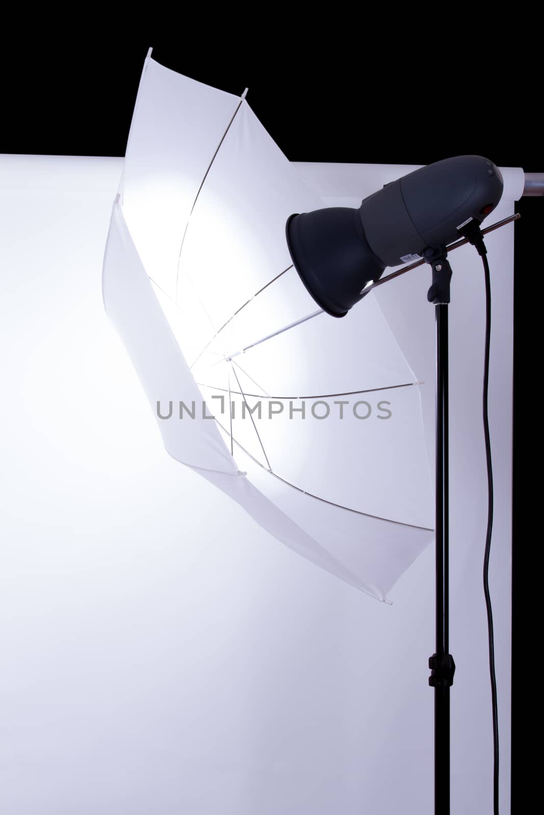 Empty photo studio with white background and lighting on dark.