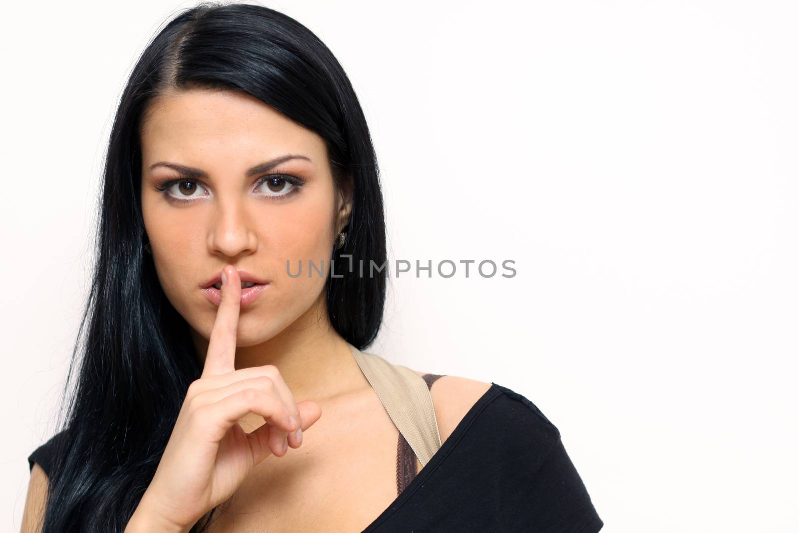 beautiful brunette with a finger on her lips showing to keep silence