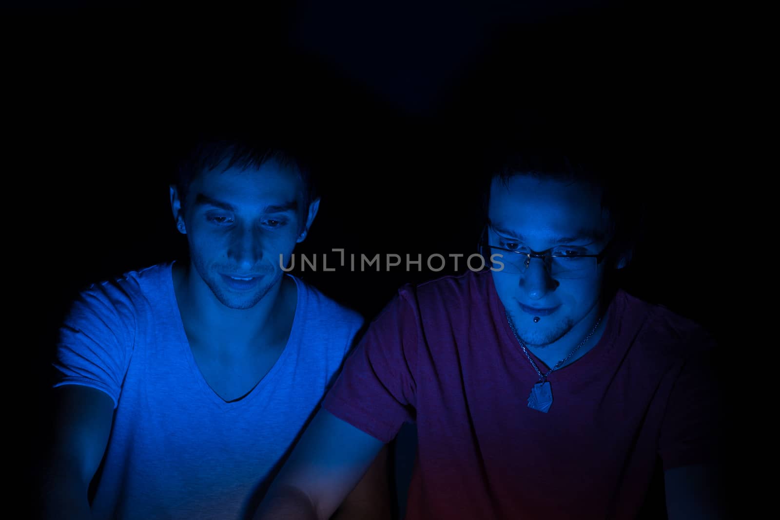 Two male friends online concentrating on the computer screen