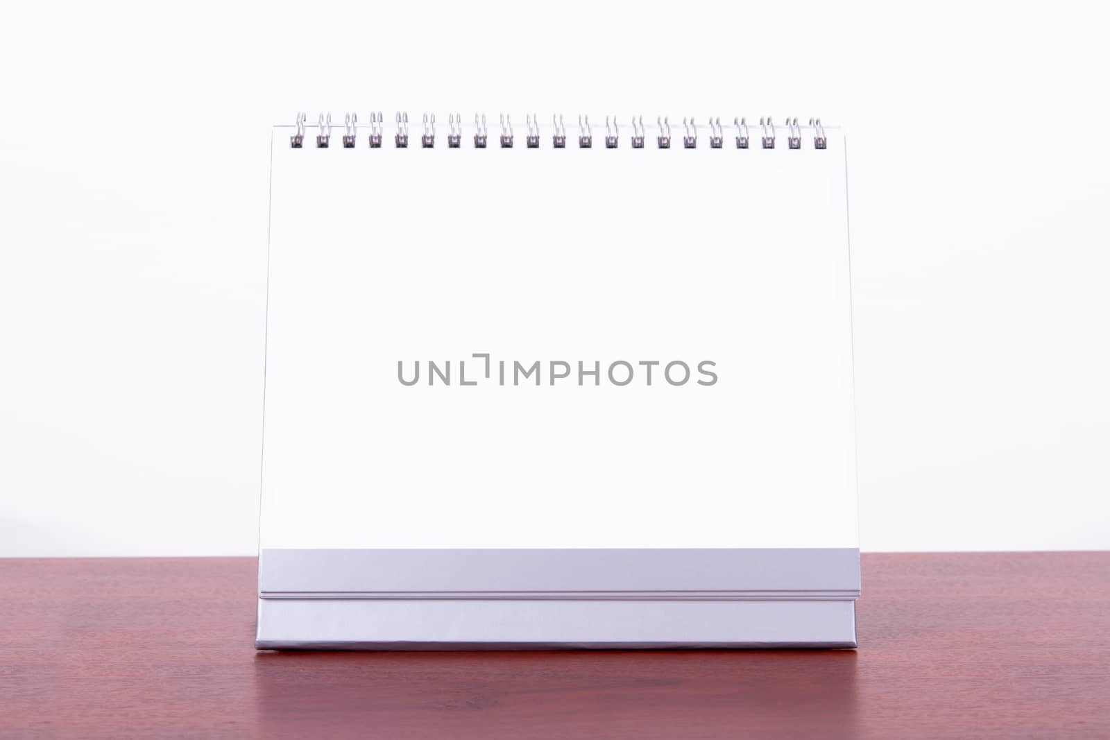 Single blank desk calendar on wooden table, isolated on white background.