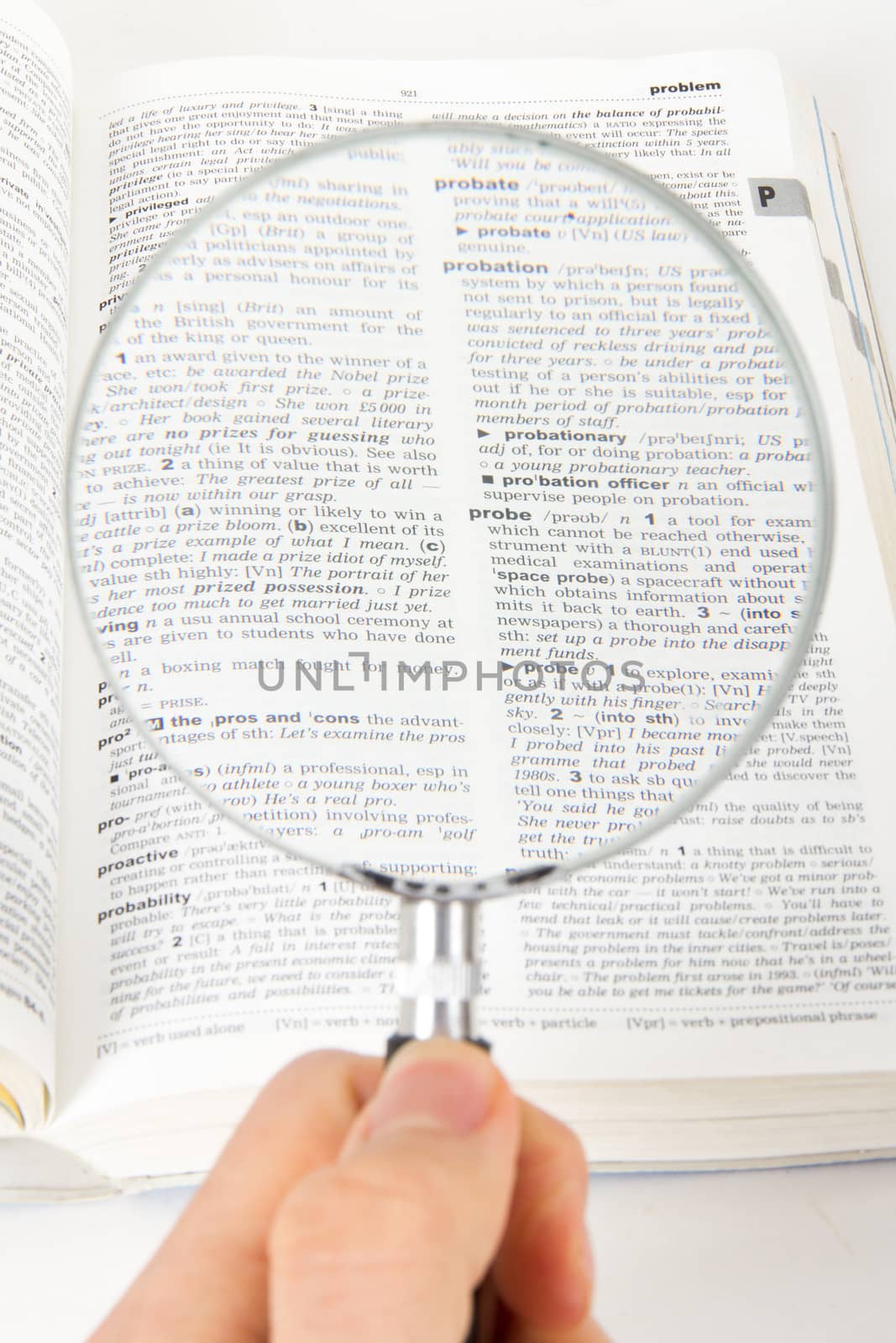 Hand holding classic style magnifying glass, searching for a word on dictionary page, isolated on white background.