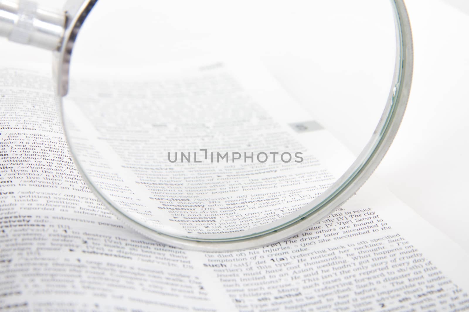 Close up of classic style magnifying glass on open dictionary book, searching words, isolated on white background.