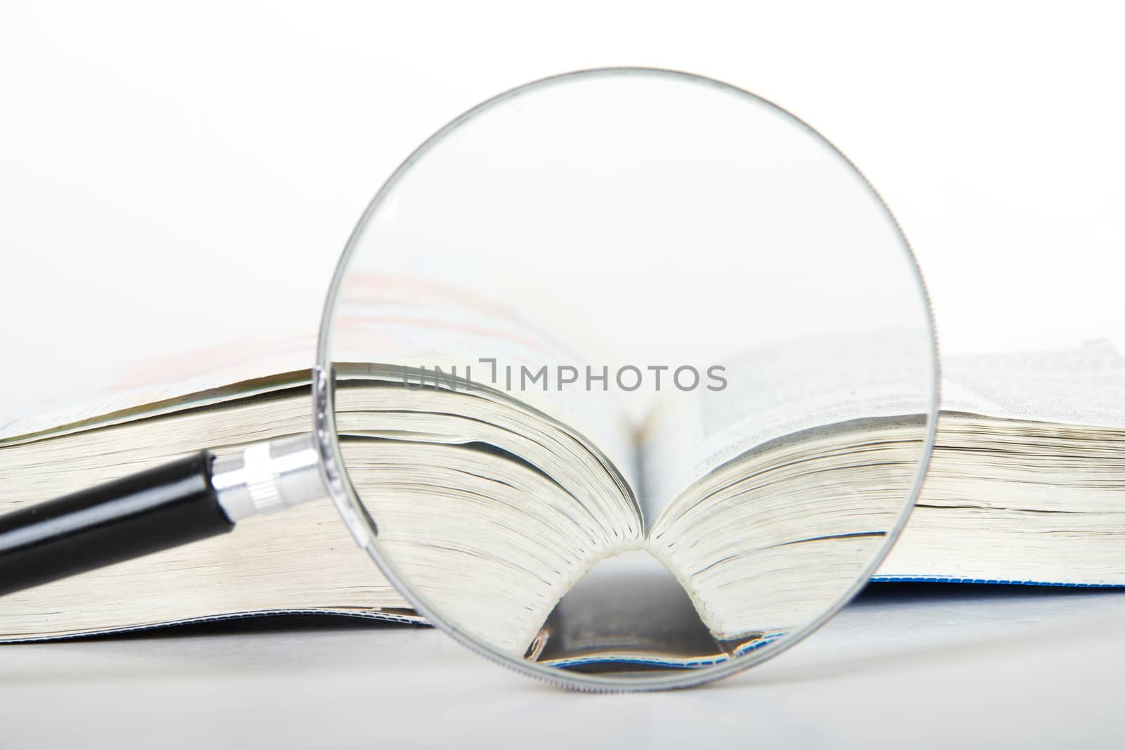 Magnifying glass and open dictionary book, isolated on white background.