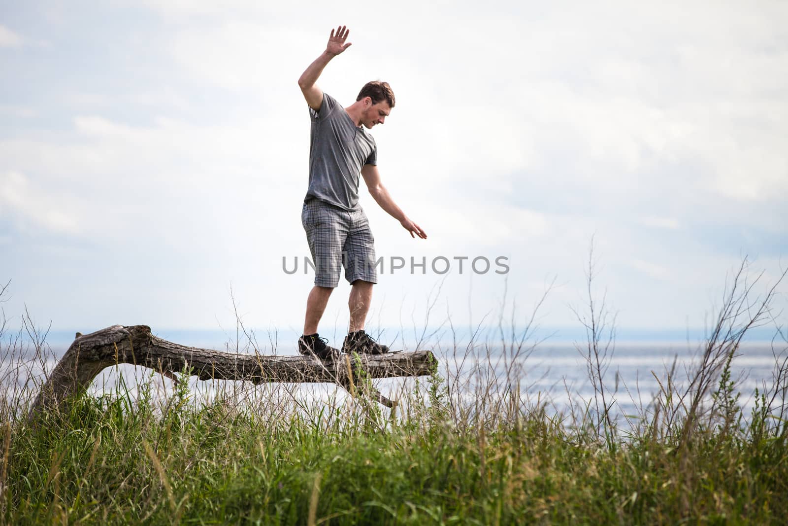 Young Adult Balancing on a dead Tree in Nature in Vacation, just for Fun