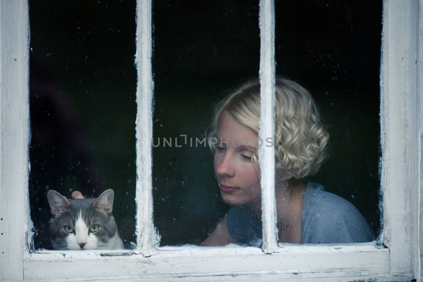 Woman and Cat Looking at the Rainy Weather By the Window Frame