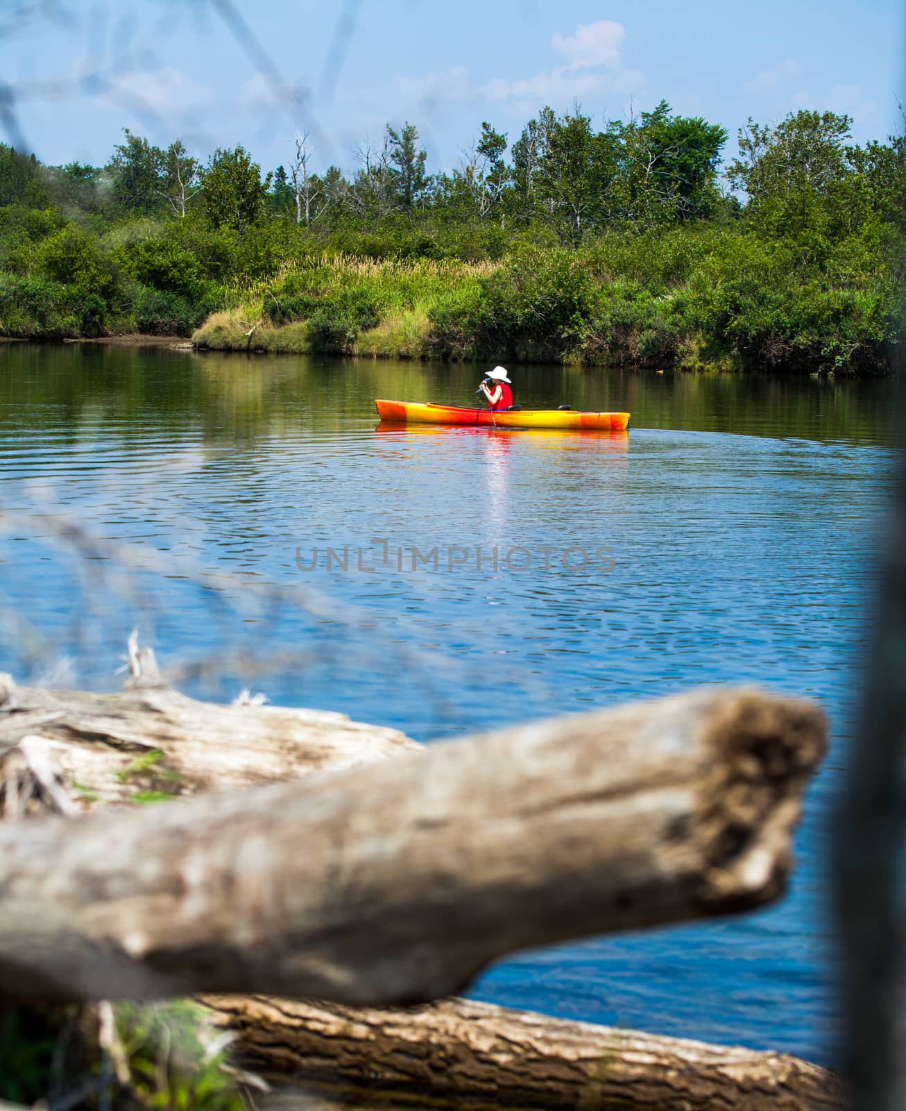 Woman With Safety Vest Kayaking Alone on a Calm River by aetb