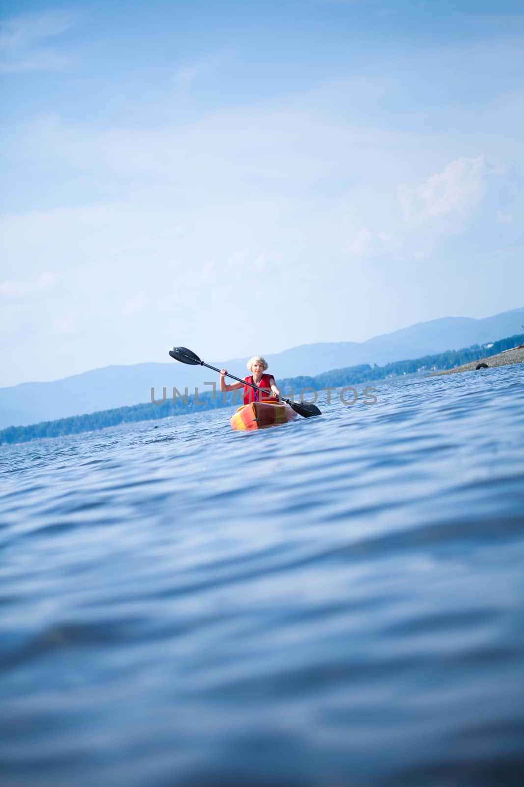 Young Woman Kayaking Alone on a Calm Sea and Wearing a Safety Vest