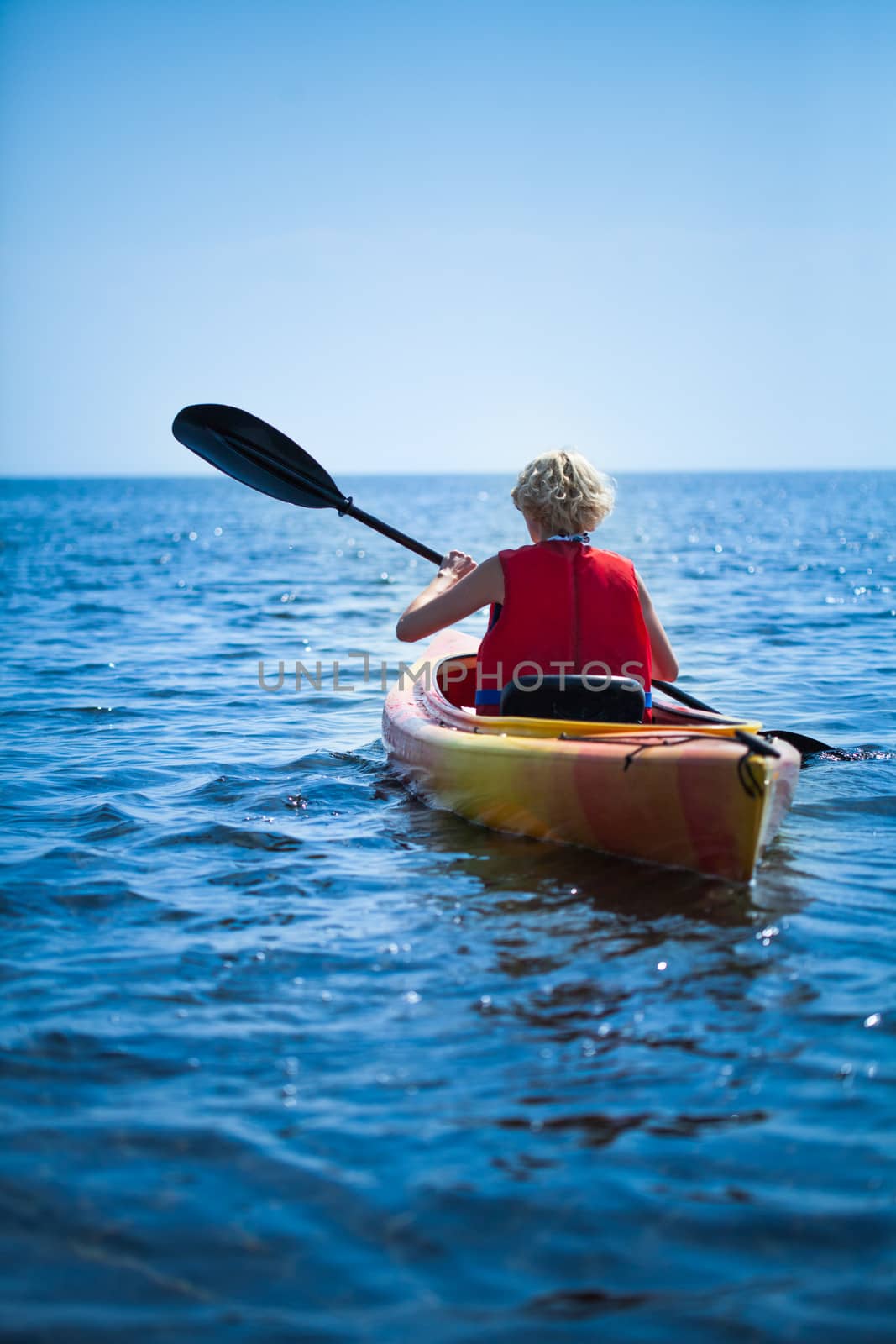 Young Woman Wearing a Safety Vest Heading out to sea Alone on Calm Water