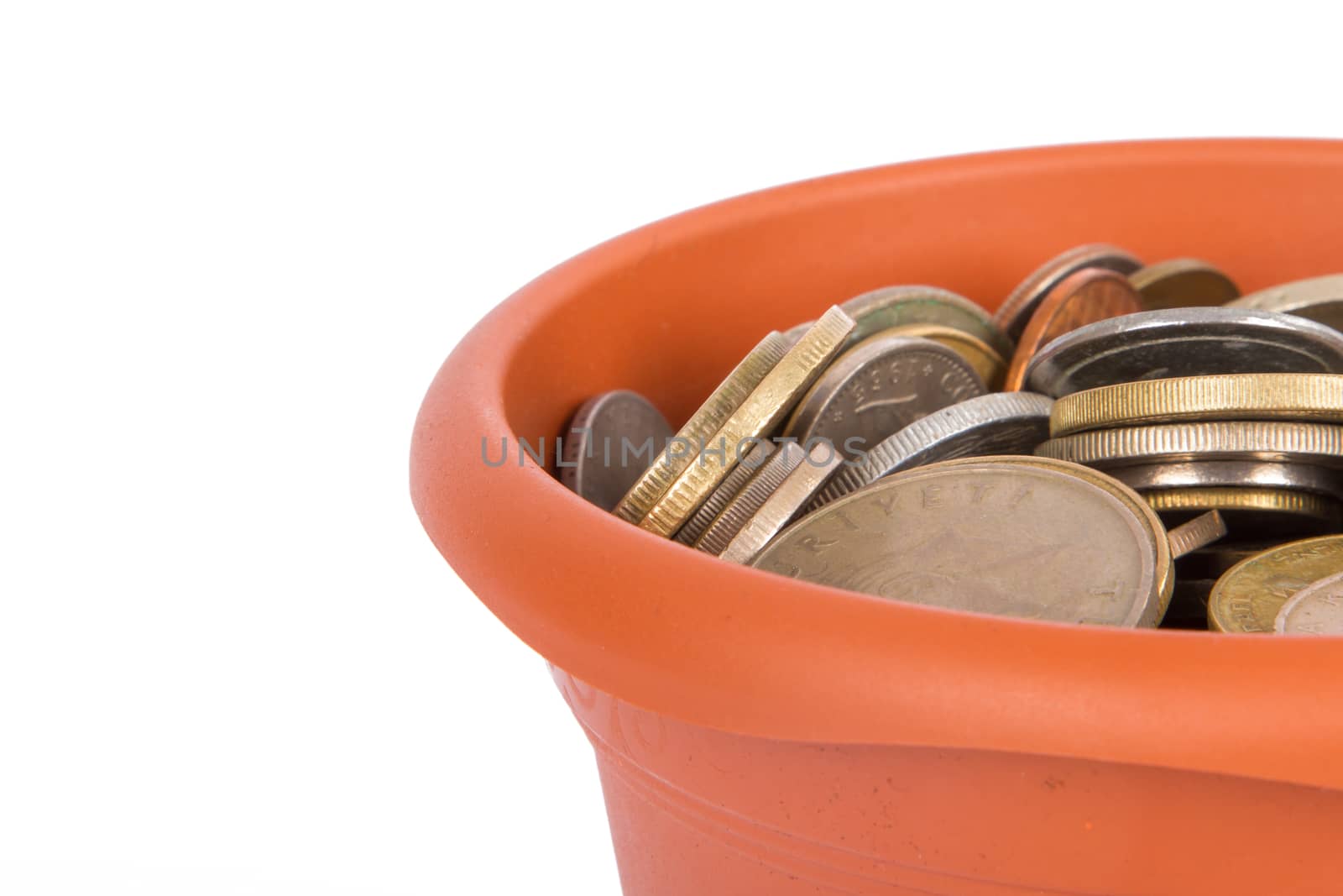 Detail view of flower pot and full of coins money inside, isolated on white background.