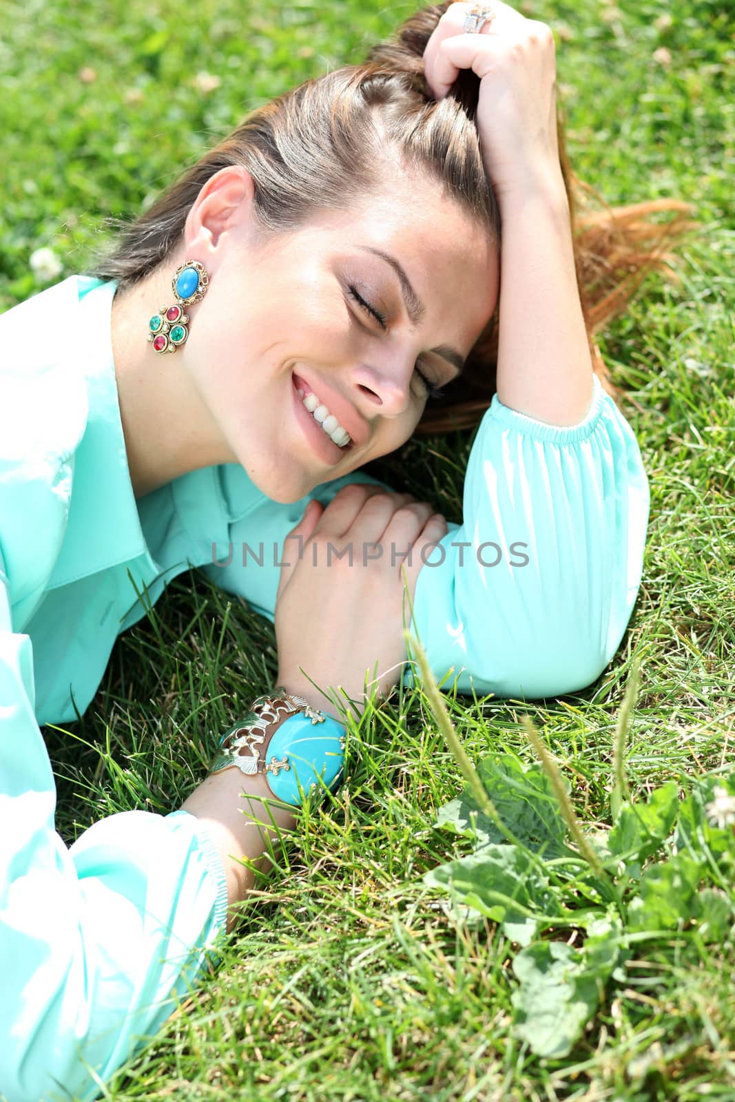 Portrait of young woman lying on a green lawn