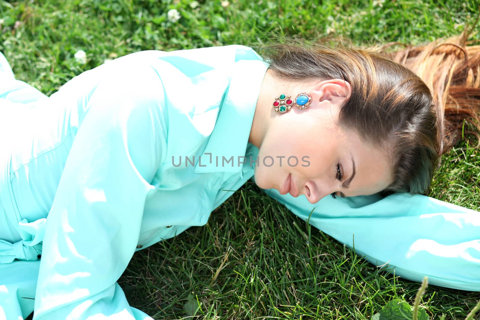 Portrait of young woman lying on a green lawn