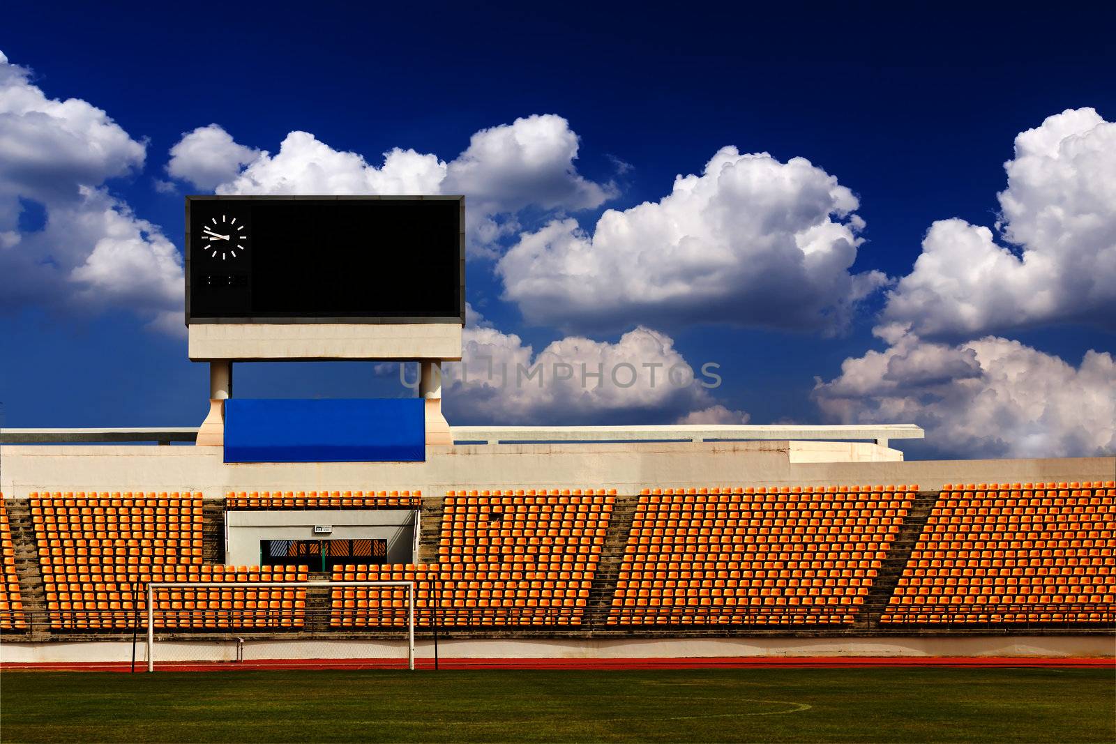 Rows of orange seats on the stadium with scoreboard displaying clock above them