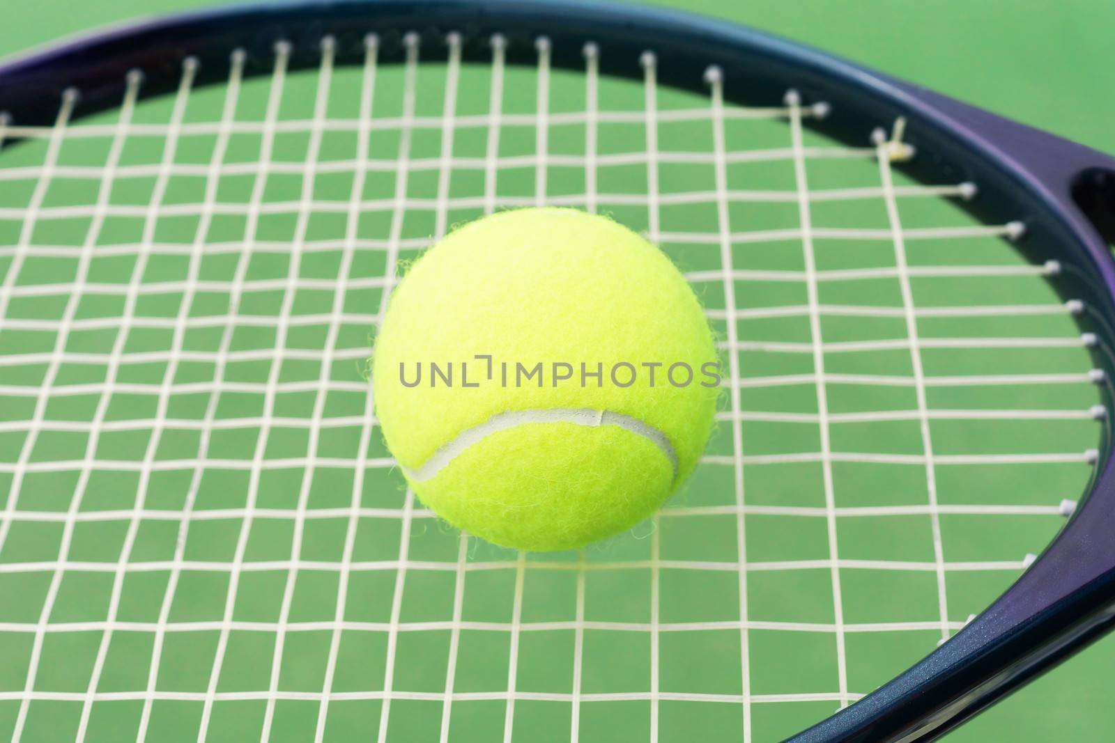 Tennis racket with ball over green hard surface court