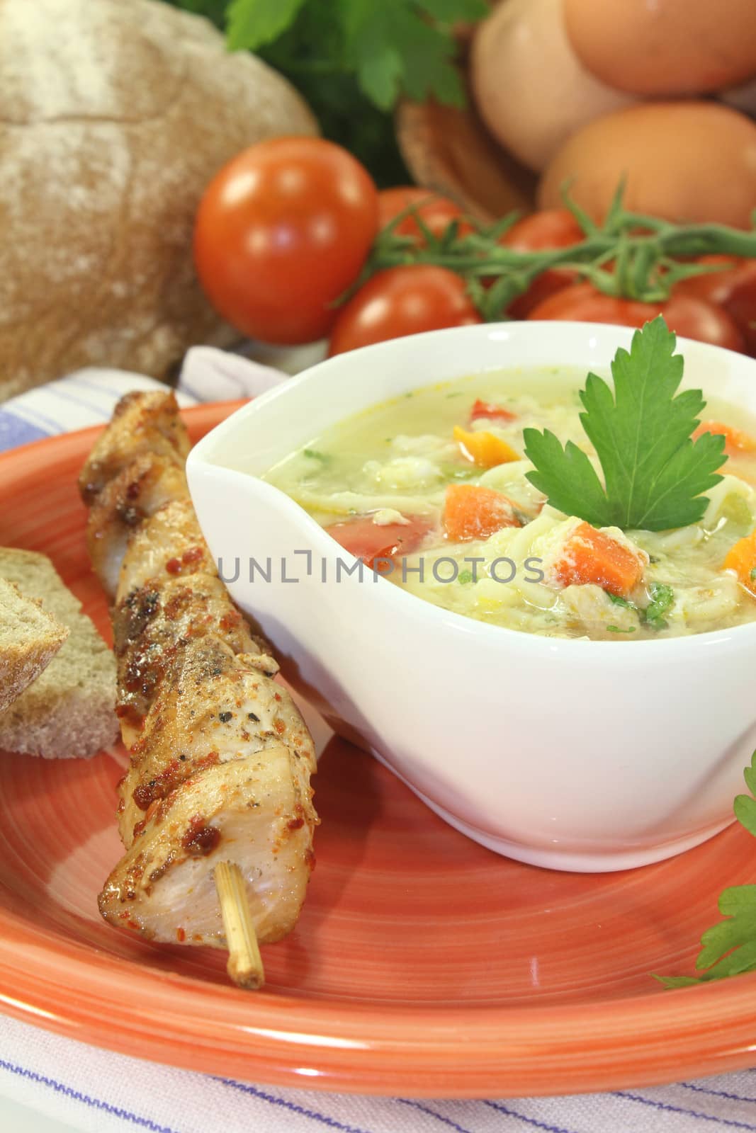 Chicken soup with eggs, noodles and tomatoes on bright background