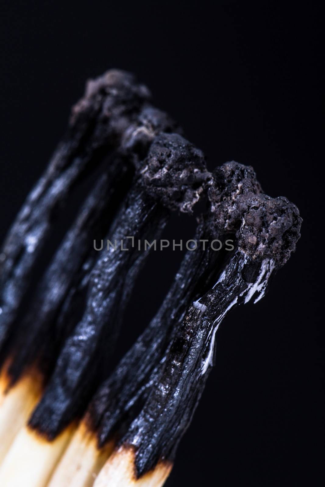 close up of group of burnt matches with depth of field on dark background.