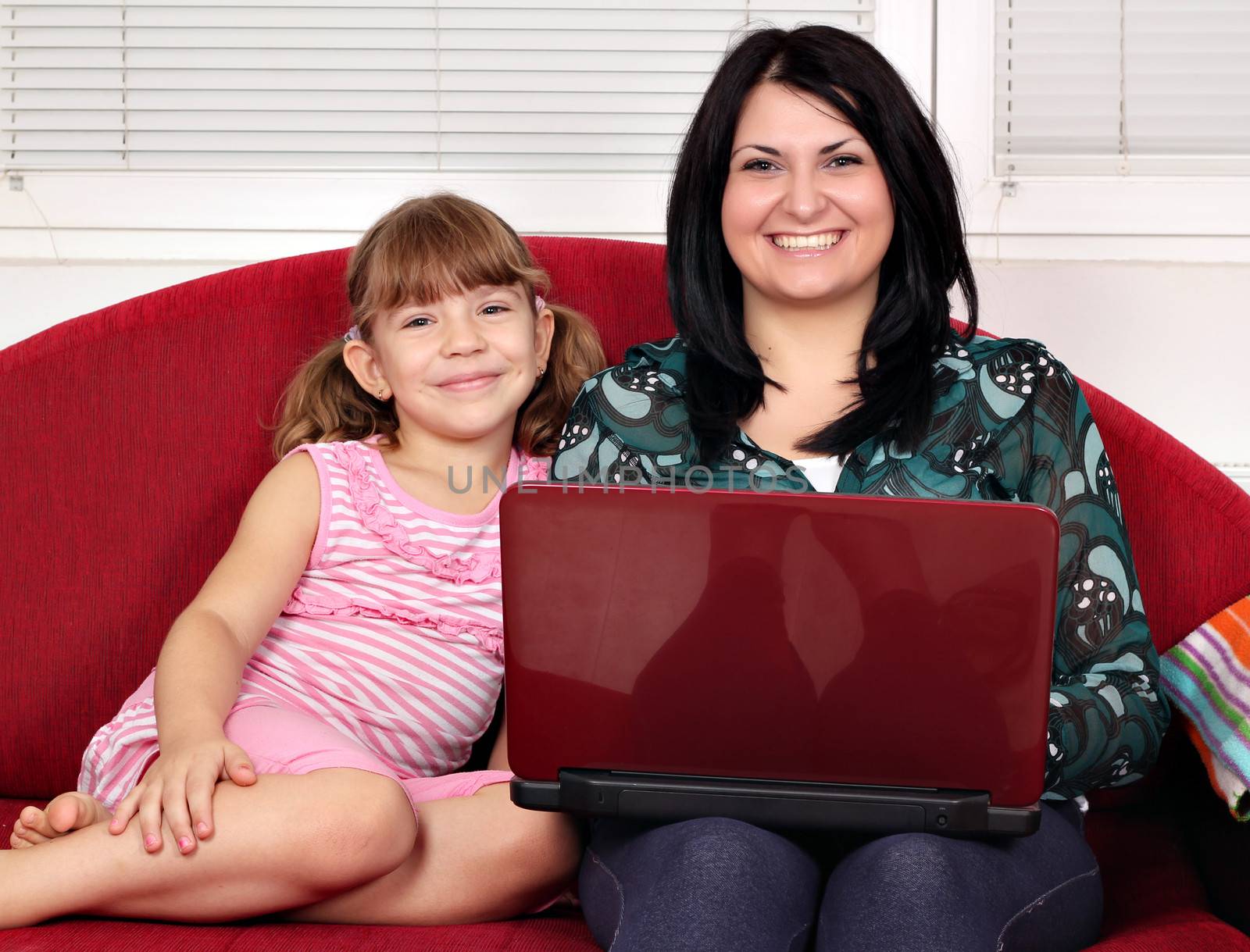 happy girls with laptop sitting on bed