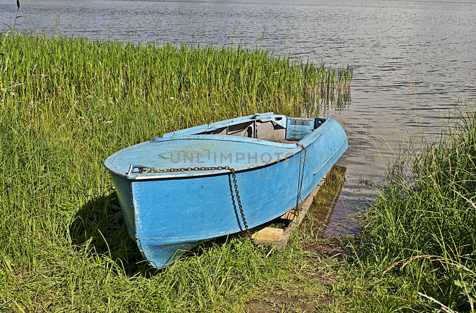 Old aluminum boat in grass by the lake