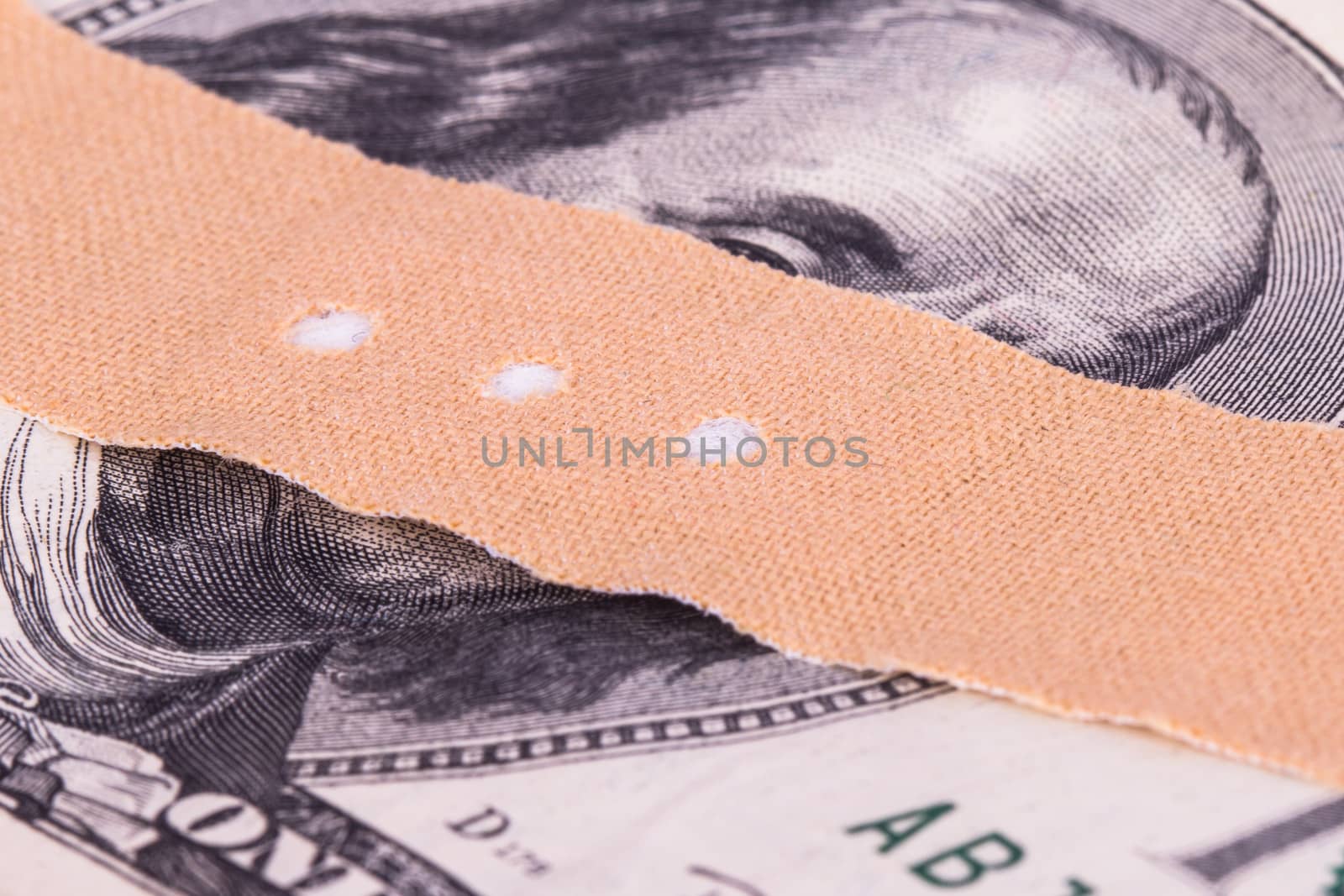 Adhesive bandage, plaster on one hundred dollar bill.