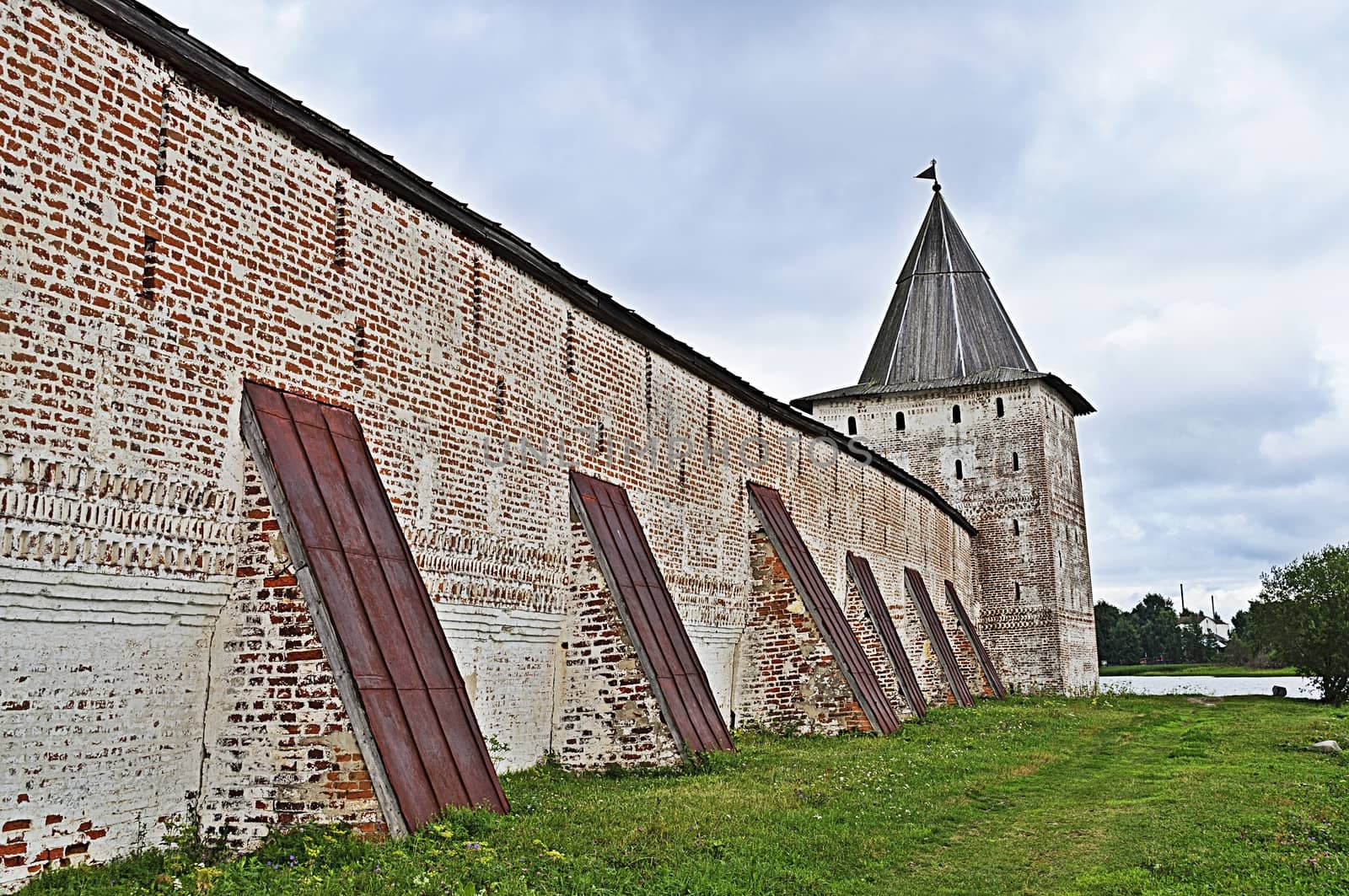 Wall with buttresses and tower of ancient monastery by wander