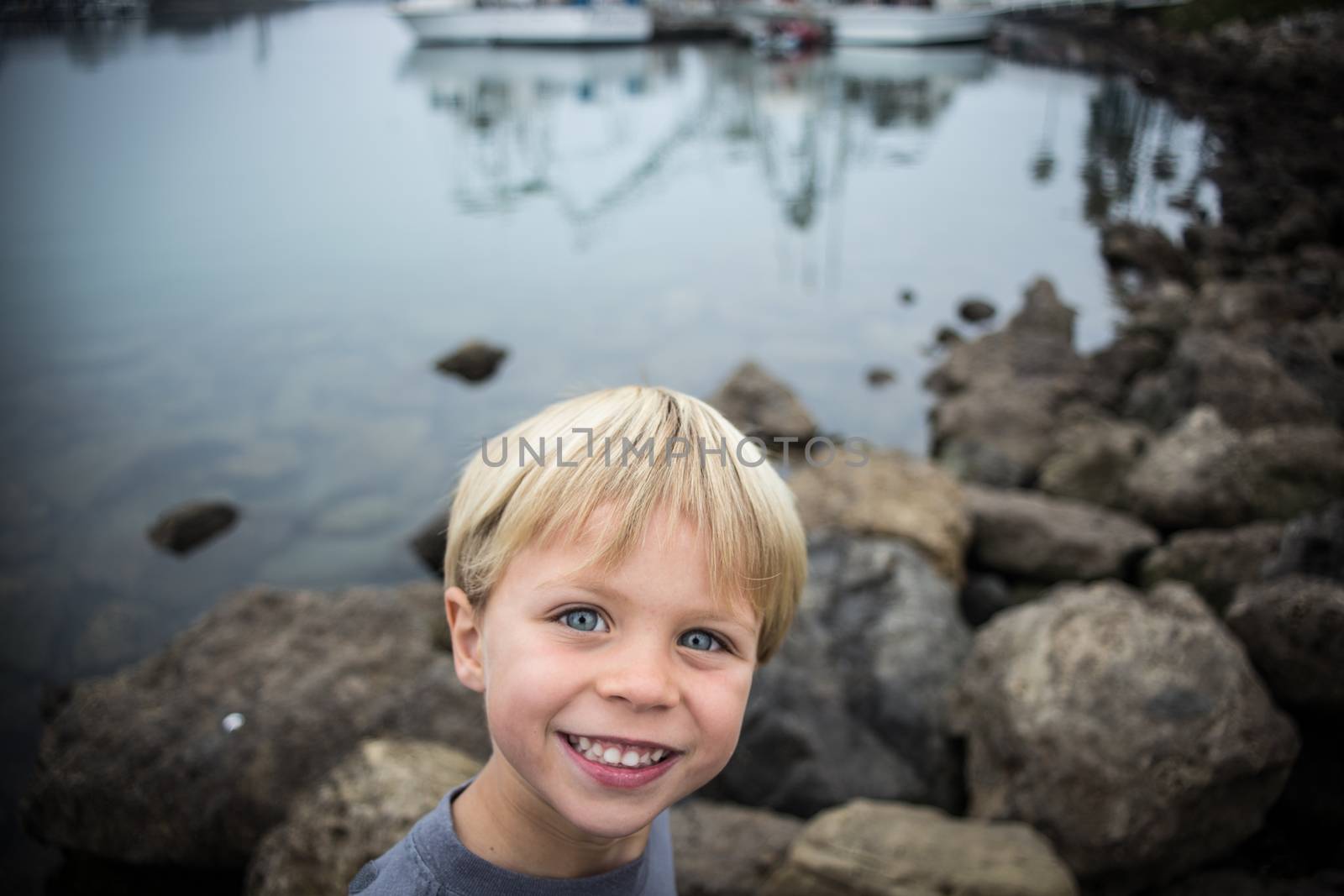 A young blonde boy happy to be outdoors exploring the details that the ocean has to offer.