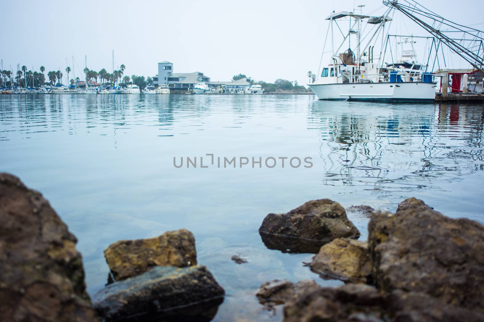 Rocks in the foreground, fishing boat in the middle ground, yachts and museum in the background.