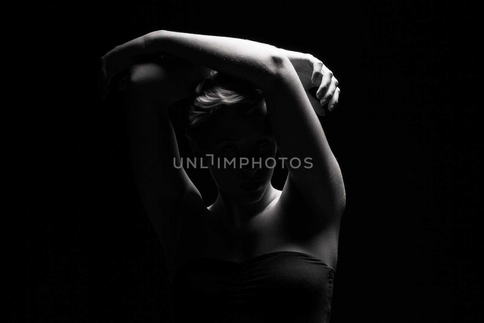 woman in black and white tense light holding arms over her head