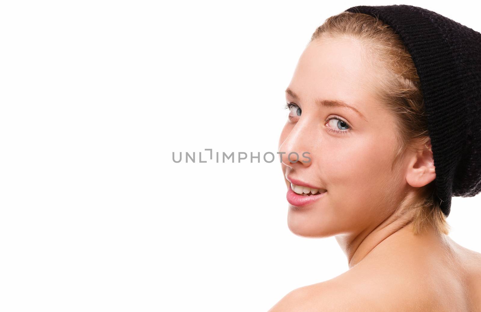 smiling young woman wearing a black hat looking over her naked shoulder on white background