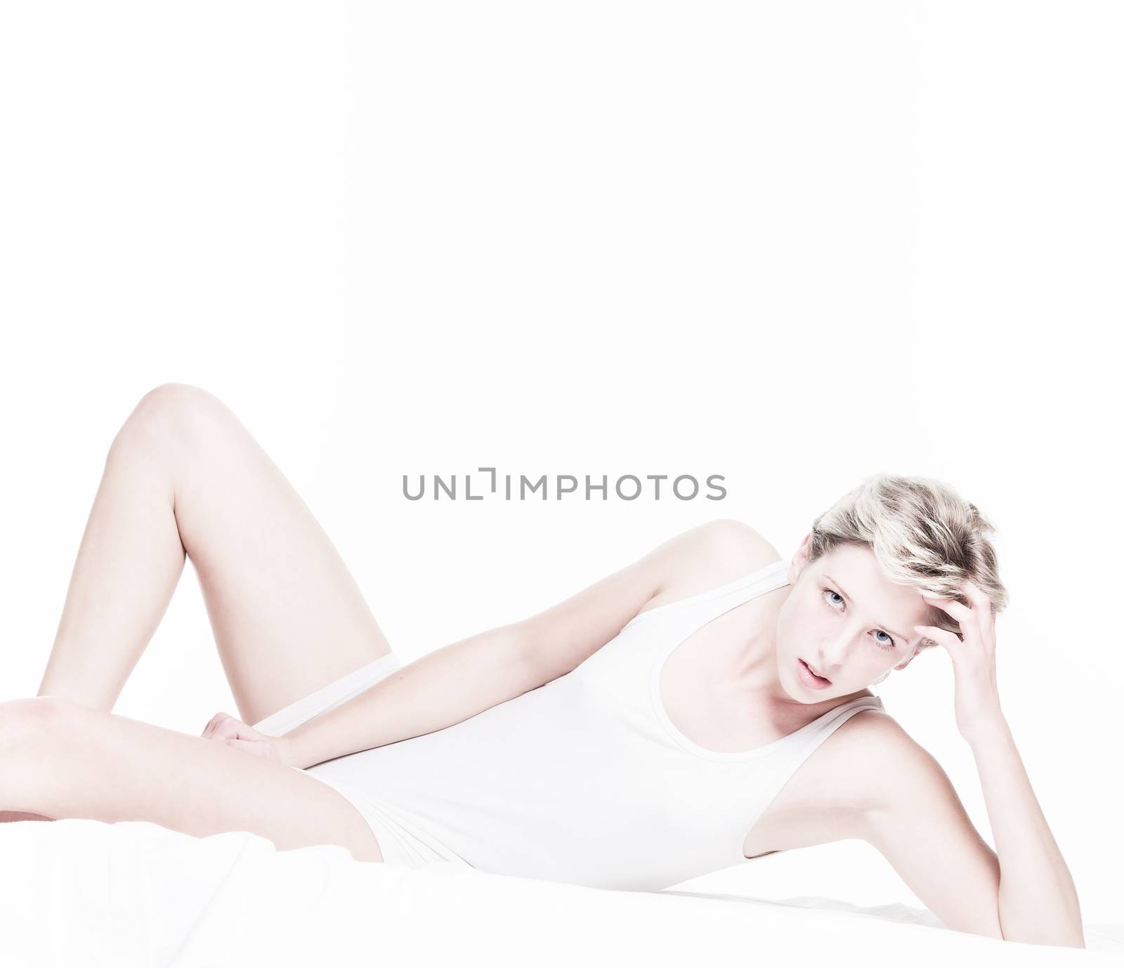 androgynous sexy woman in bed on white background
