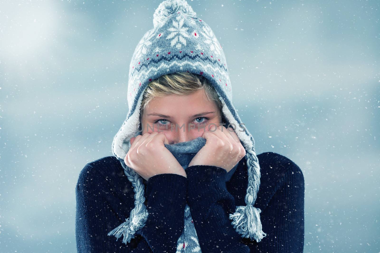 freezing young woman hiding behind her scarf in snowfall