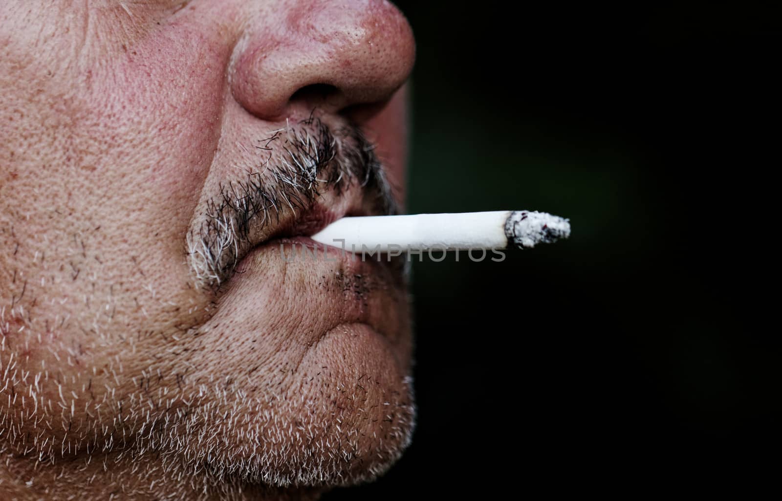Smoking a cigarette against a dark background