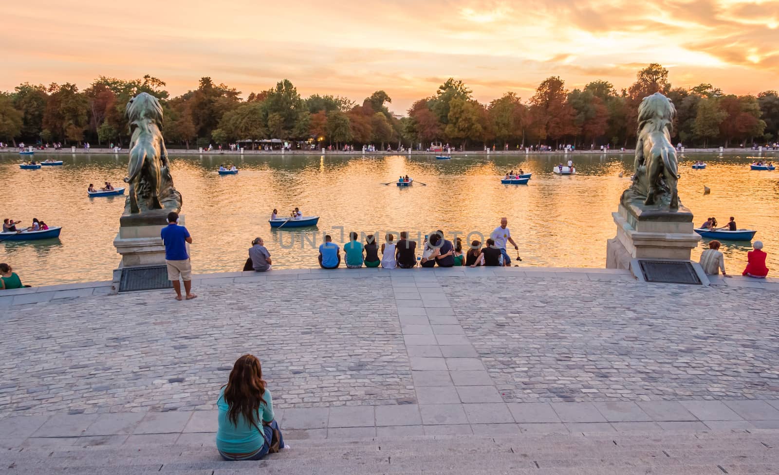 Madrid, Spain - September 02, 2013: People watching sunset in front of Buen Retiro park lake, sitting on the monument stairs to Alfonso XII, Madrid, Spain