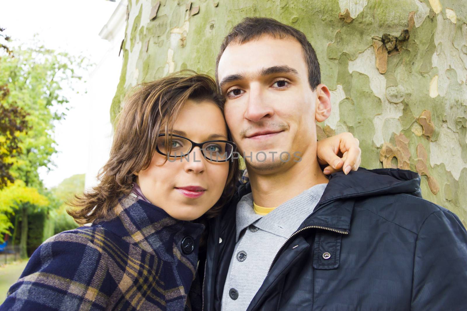 Portrait of love couple embracing outdoor in park looking happy by Tetyana