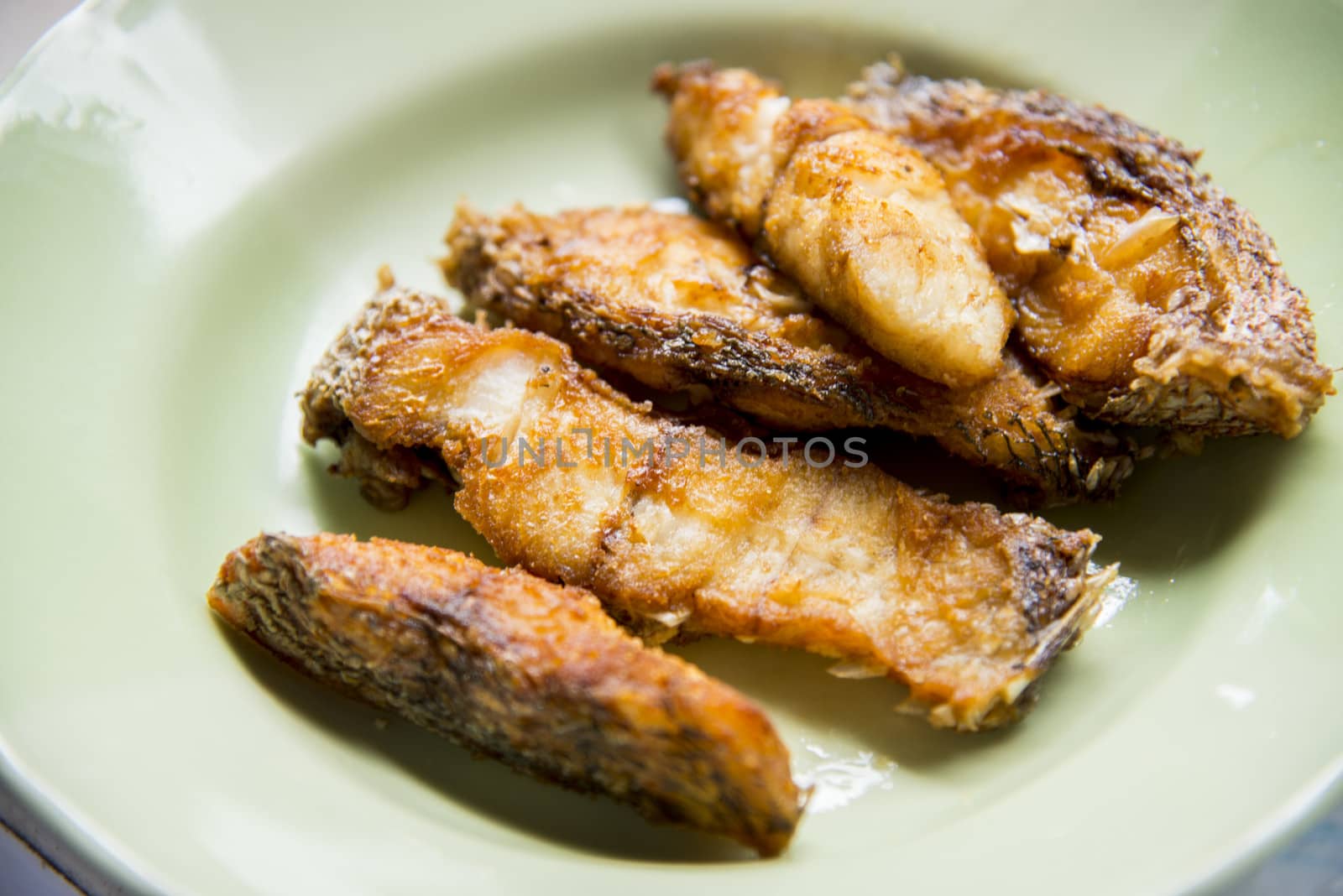Pieces of fried fish in a dish by gjeerawut