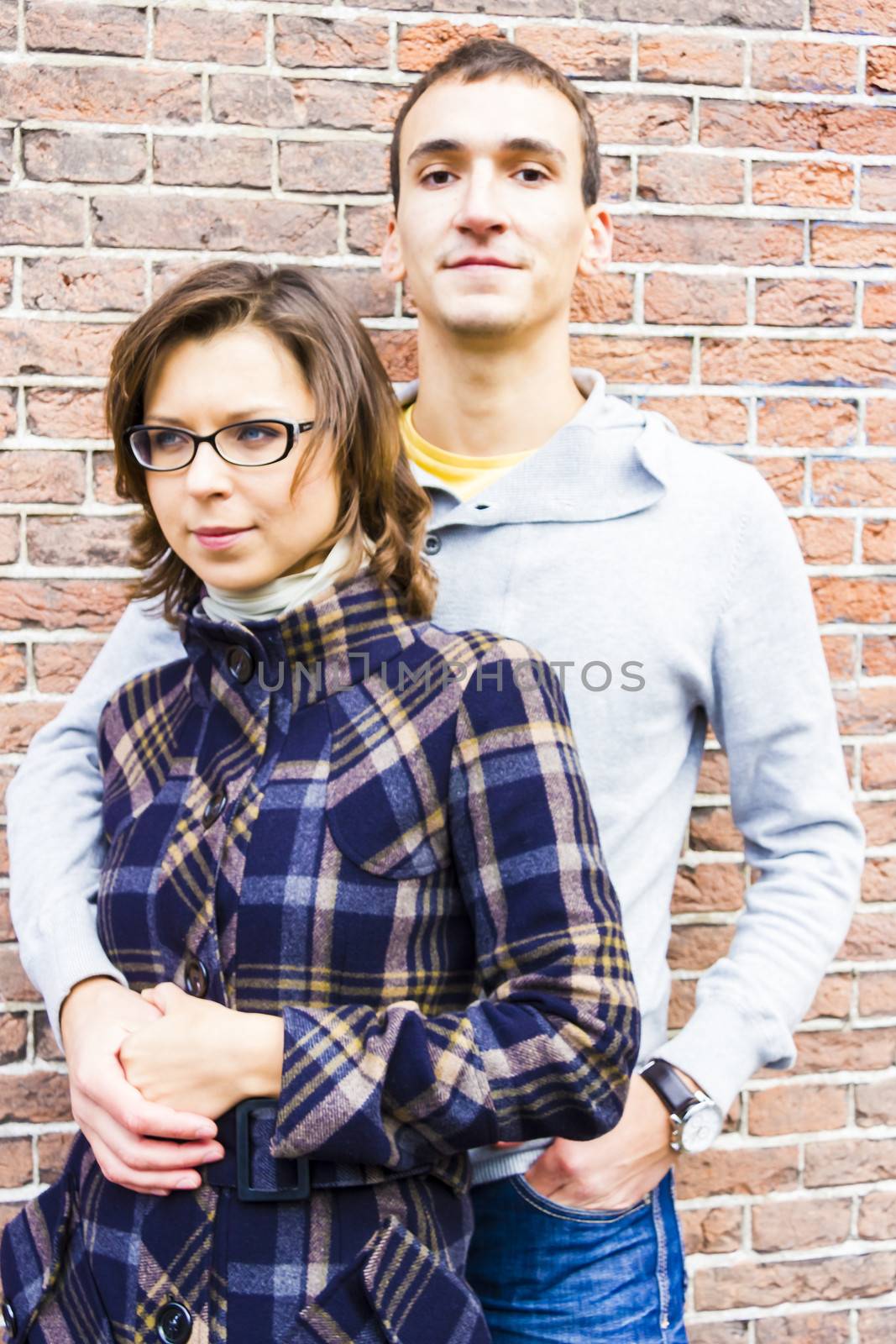 Portrait of love couple embracing looking happy against wall bac by Tetyana