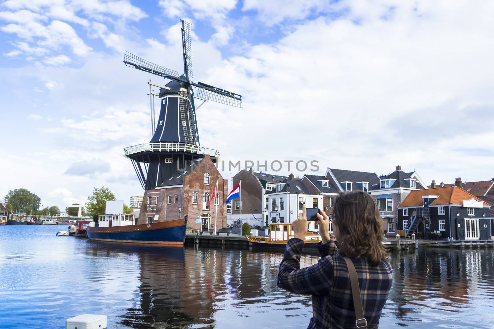 Tourist girl is taking pictures of traditional Dutch windmill by Tetyana