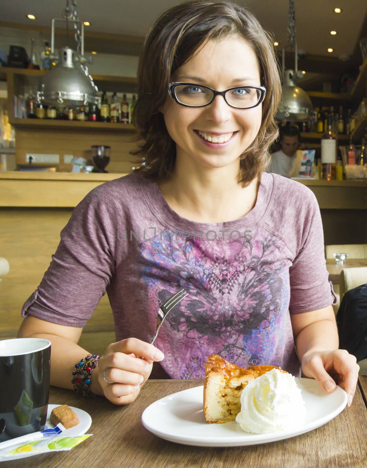 Smiling woman at cafe eating apple cake dessert with cream by Tetyana